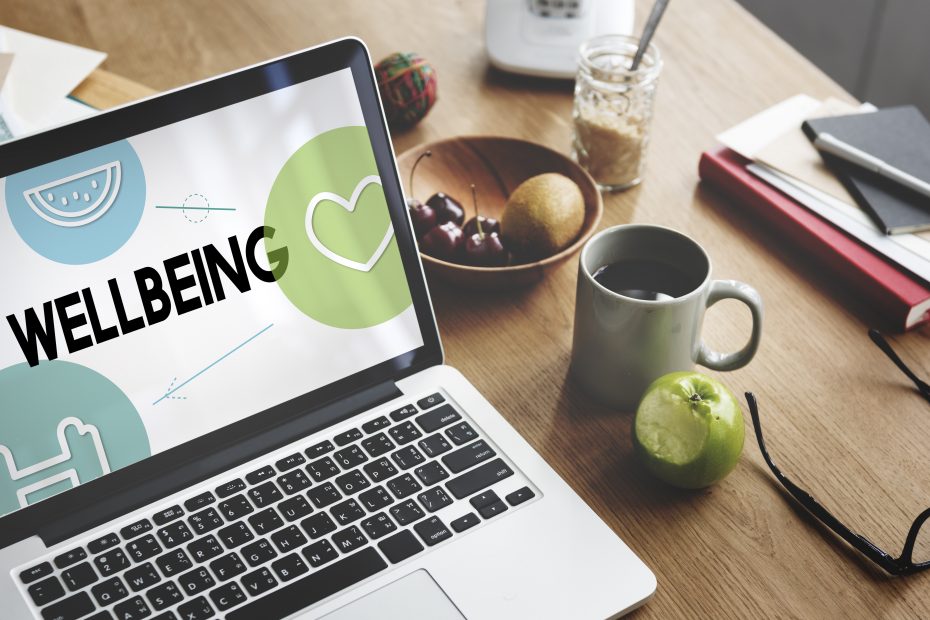 An open laptop on a desk with the word wellbeing on the screen